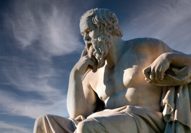 Marble statue of a bearded Greek philosopher resting his chin on his hand against a blue sky
