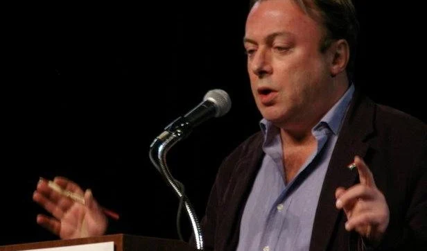 Christopher Hitchens speaking at a podium microphone, gesturing with both hands