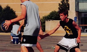Cropped view of a young teen playing defense against a taller player with a basketball outdoors