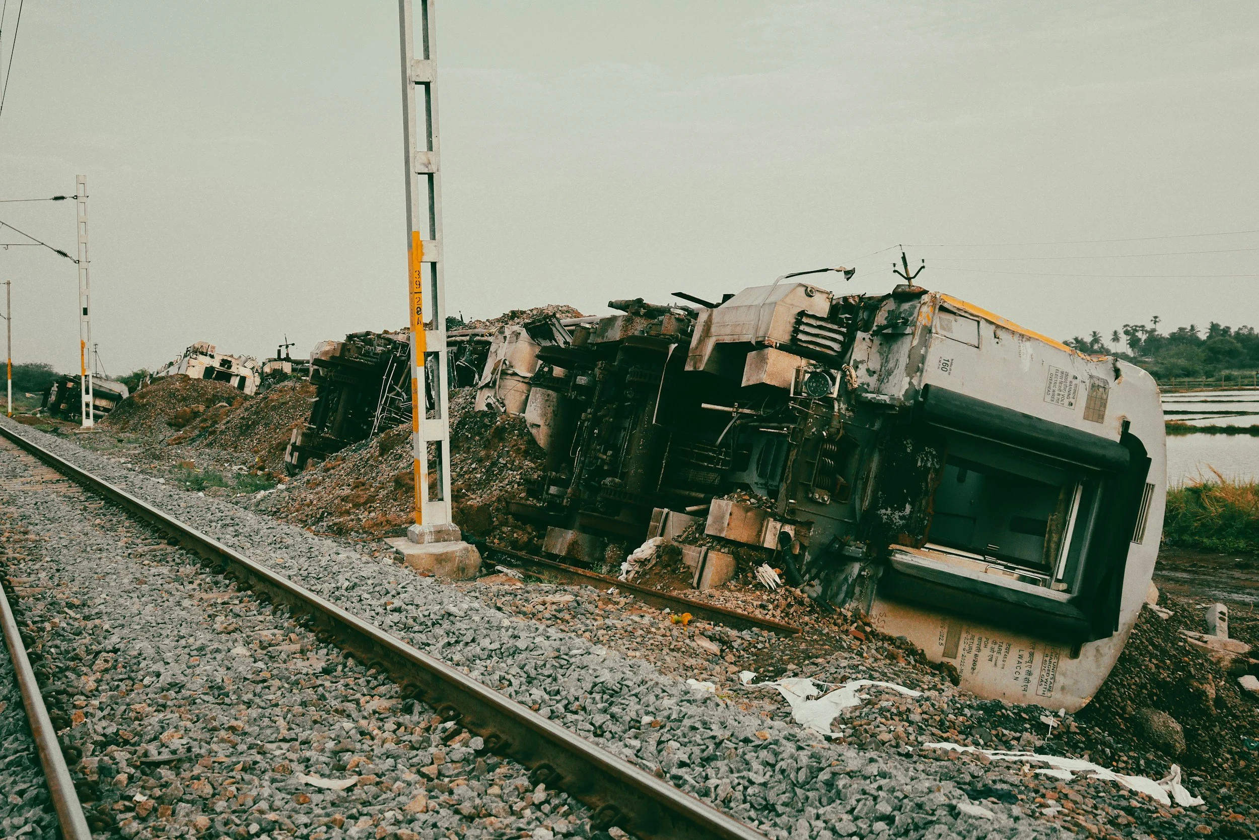 Derailed train cars lying on their sides in gravel beside railway tracks