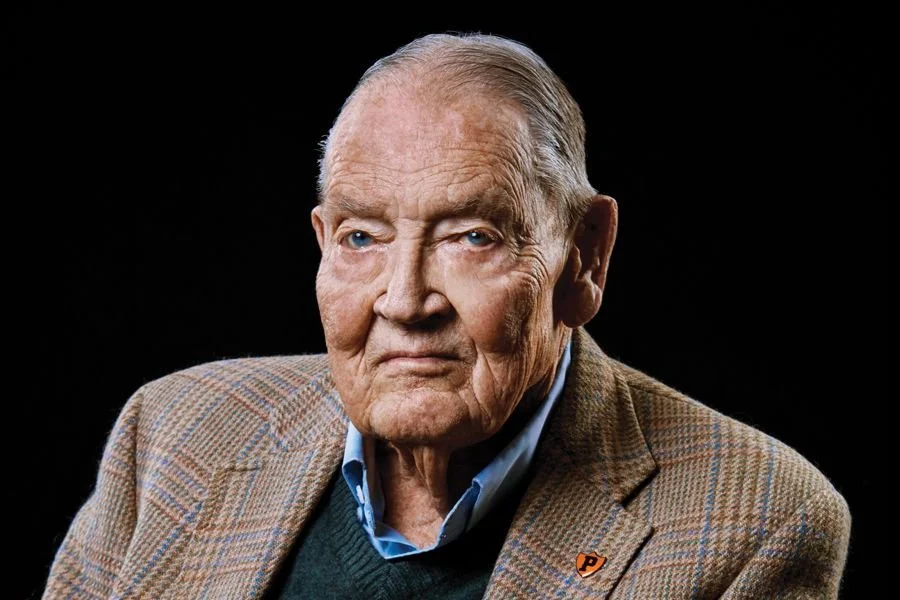 Portrait of Jack Bogle, an elderly man in a plaid tweed jacket against a black background