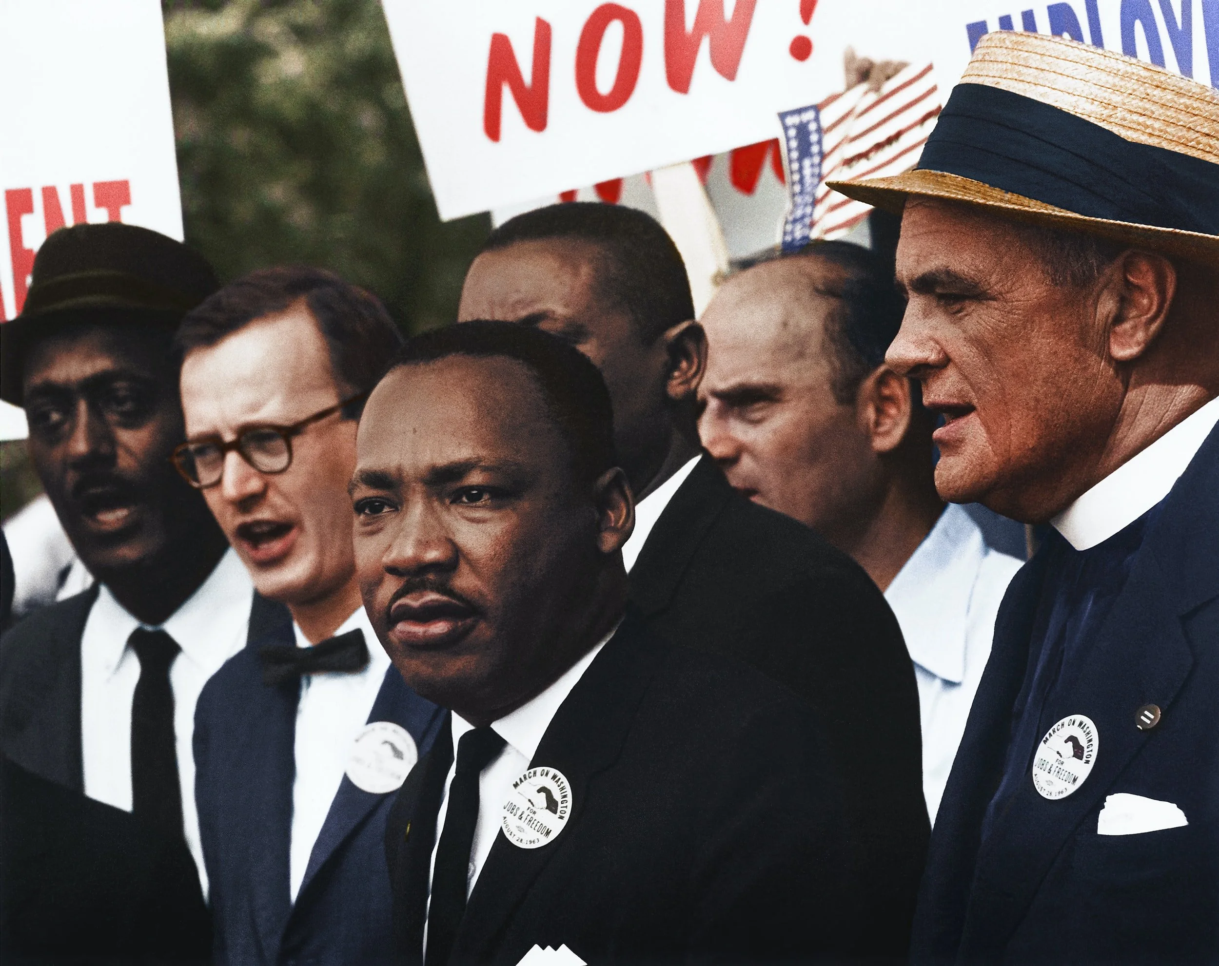 Martin Luther King Jr. with other marchers wearing March on Washington buttons, protest signs behind them