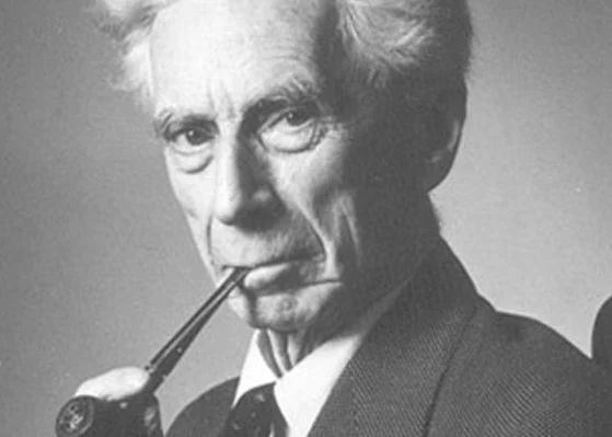 Black and white portrait of Bertrand Russell, an elderly man with white hair, holding a pipe in his mouth