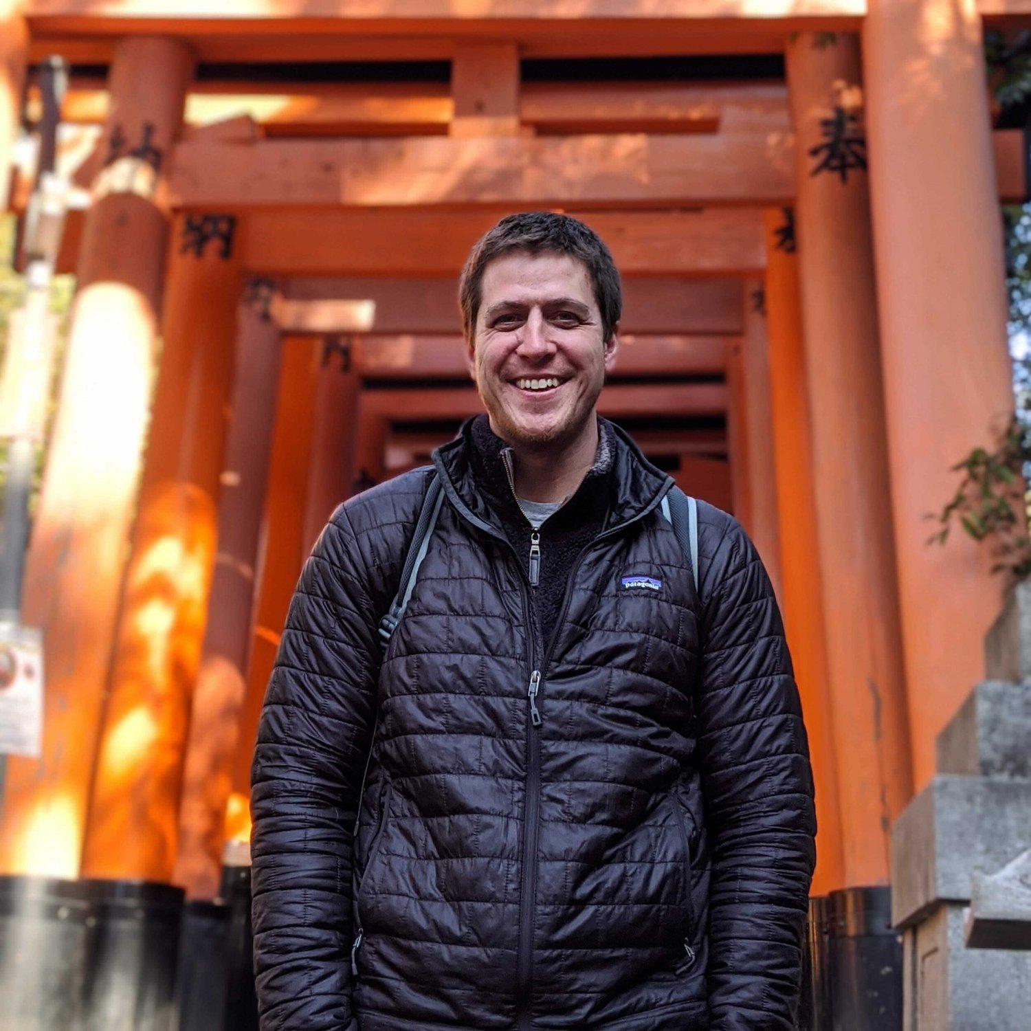 Brett, smiling, under the orange gates at Fushimi Inari in Kyoto