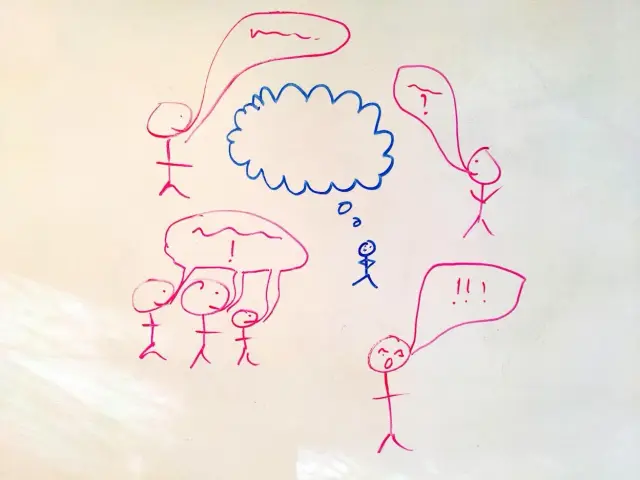 Whiteboard sketch: a small blue stick figure with an empty thought cloud, surrounded by pink stick figures talking