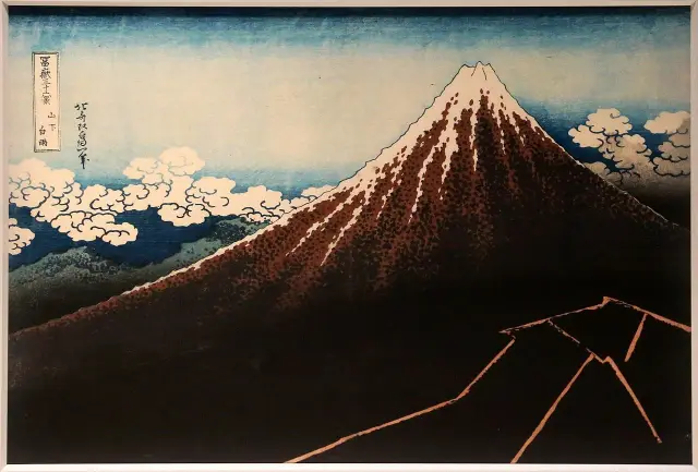 Hokusai woodblock print of Mount Fuji with a snowy peak, white clouds, and lightning near its dark base