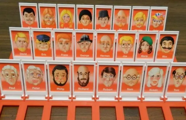 Close-up of a red Guess Who game board with rows of cartoon character faces like Joe, Maria and Richard